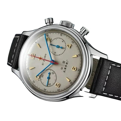 Vintage-style wristwatch with detailed face and black leather strap on a reflective surface.